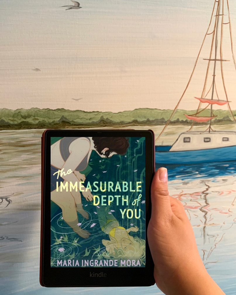 a photo of an ereader showing the cover of The Immeasurable Depth of You against a painting of a boat