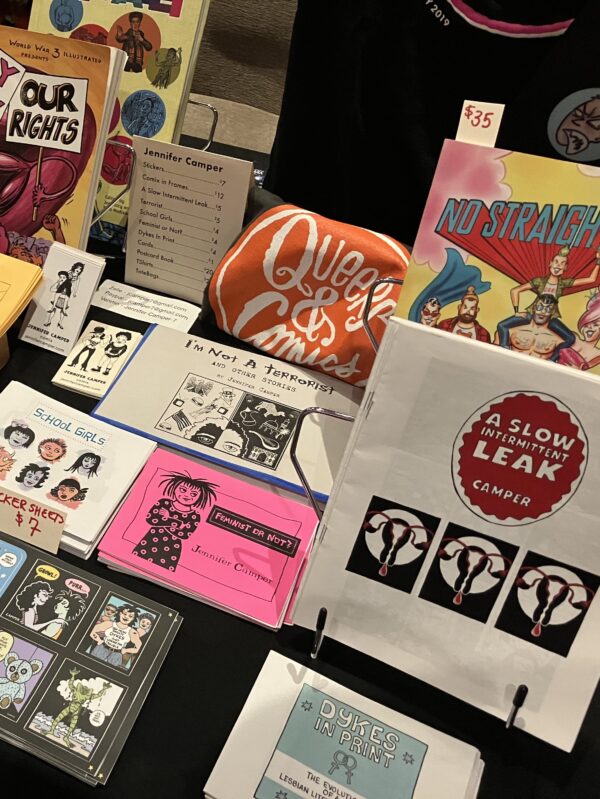 a photo of Jennifer Camper's table of zines, sticker sheets, and books