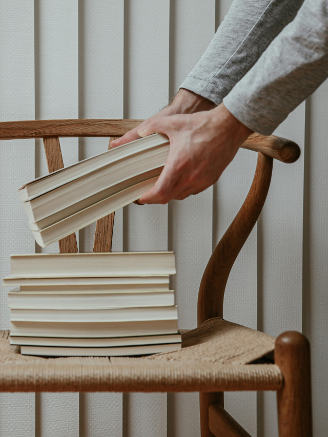 hands placing a stack of books on a chair